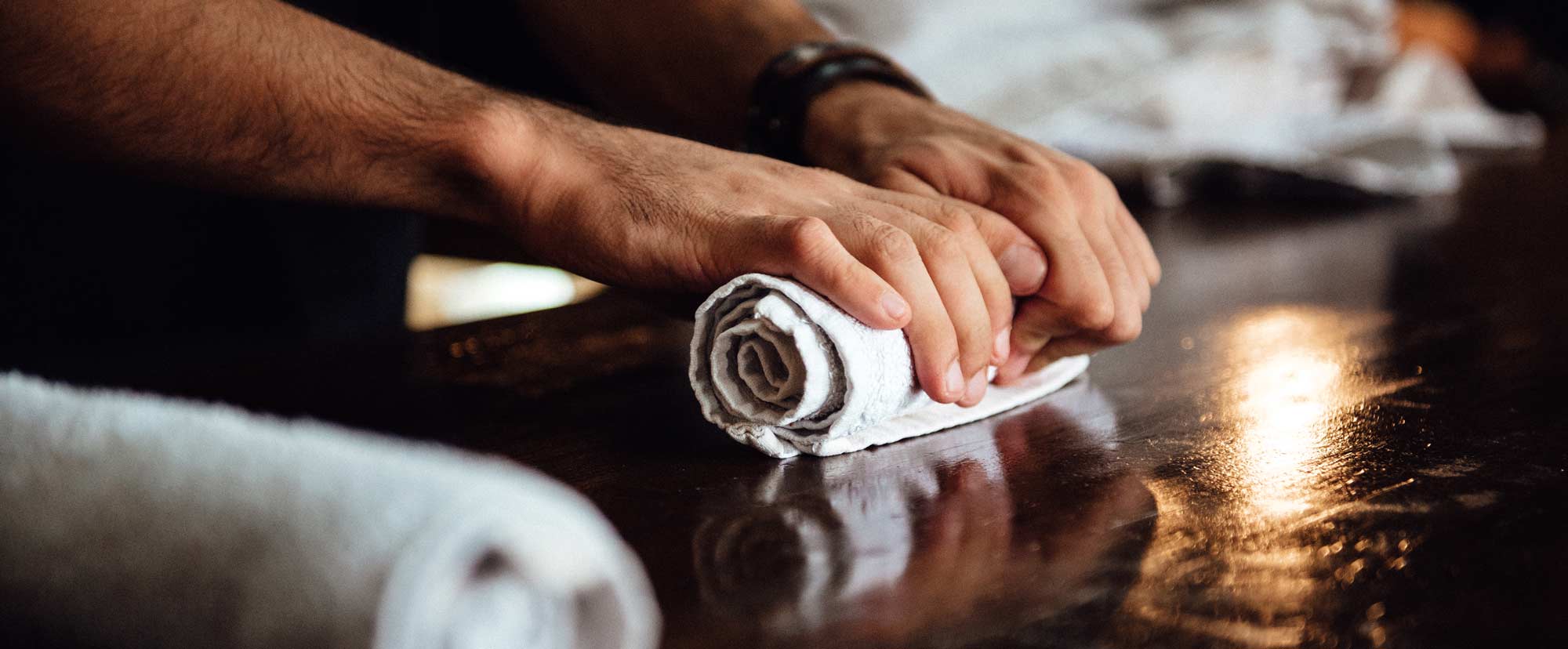 Man wrapping a towel on a wooden counter