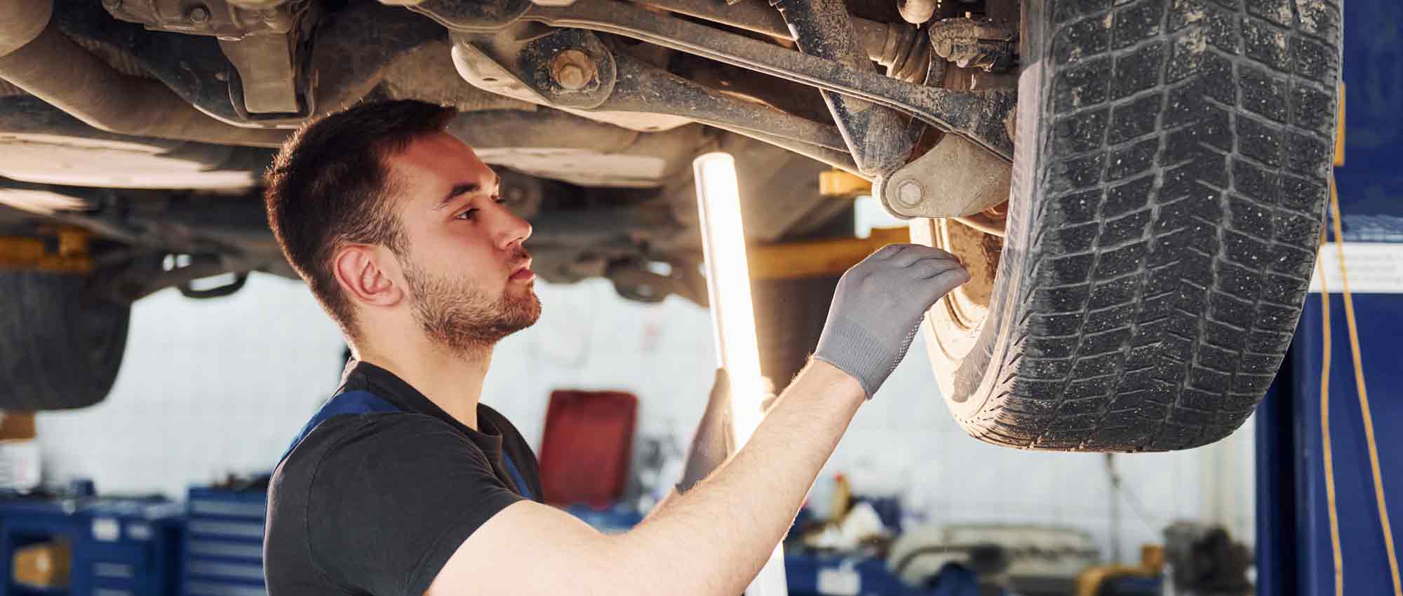 A mechanic checking the wheel of a suspended car
