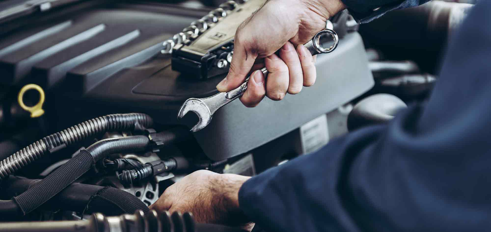 A mechanic holding a wrench over an engine